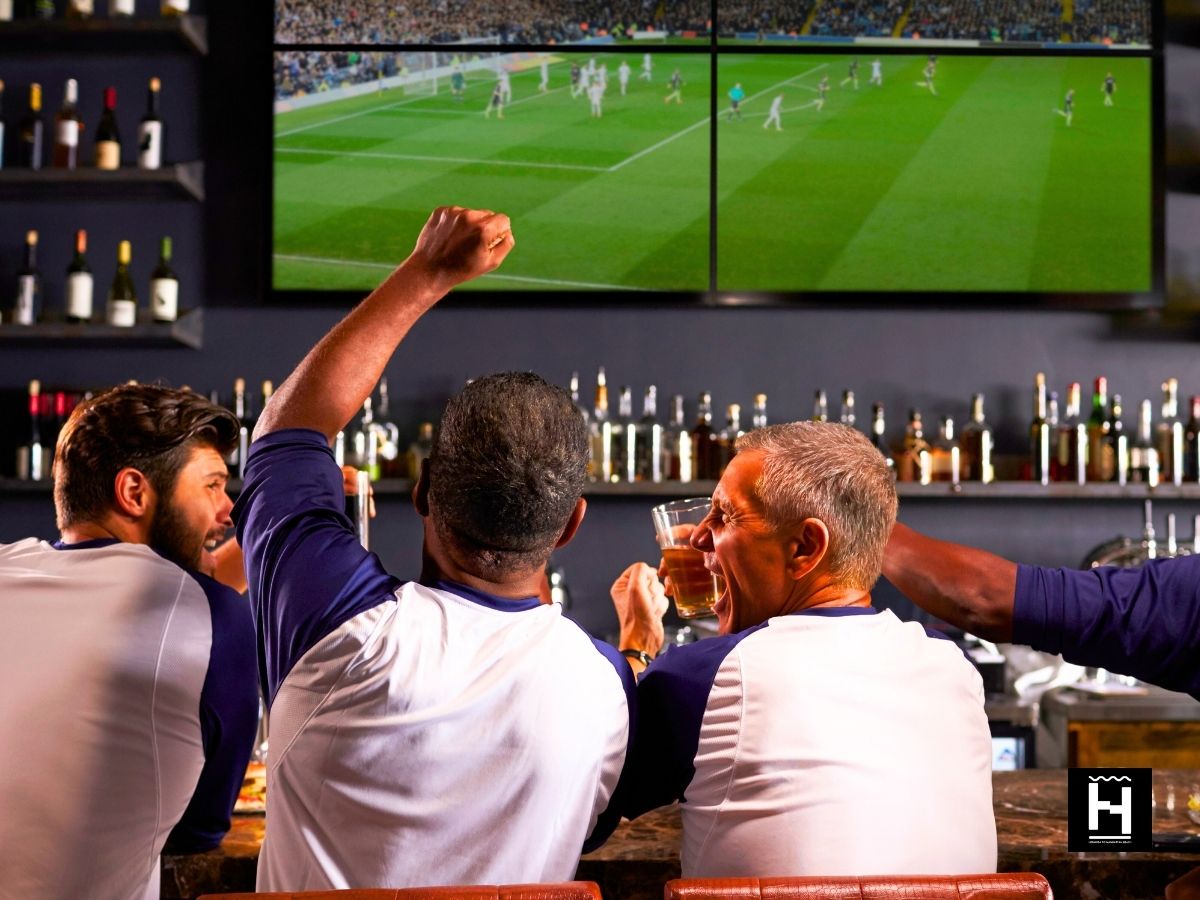 people cheering in front of tv at a sports bar watching sports