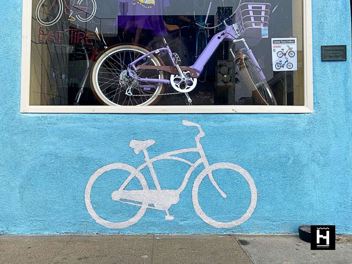white bike street art painted on a blue wall outside of bike store hermosa beach cyclery